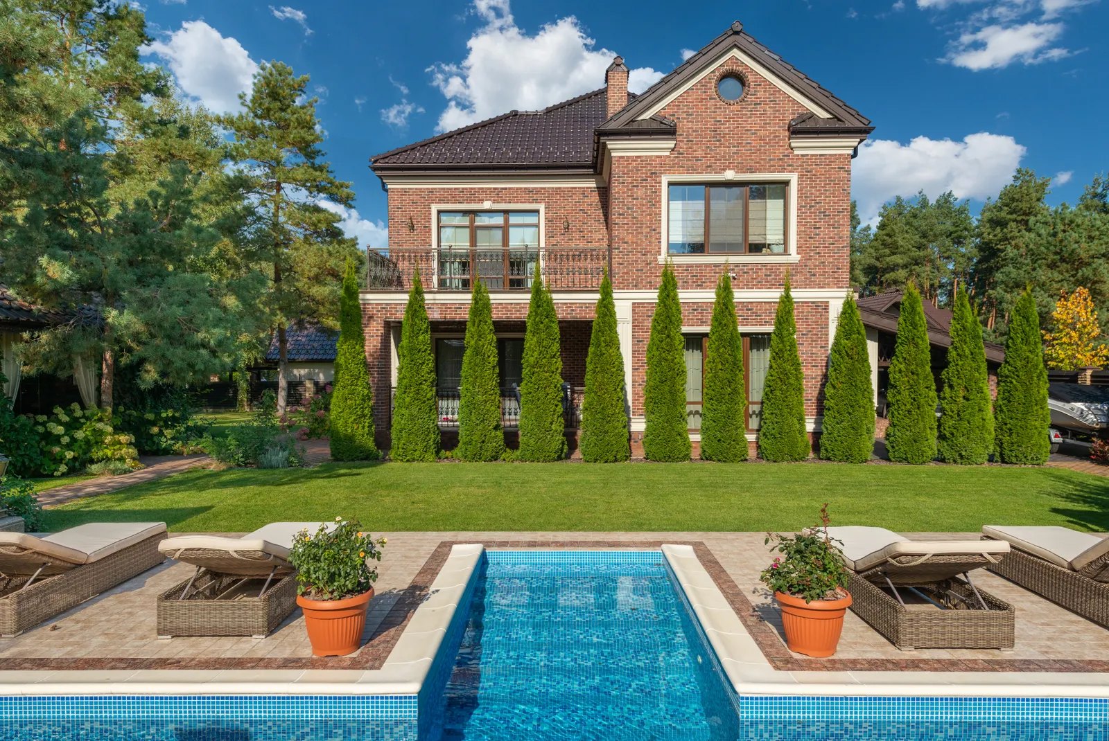 Brick home with a rectangular inground pool and patio